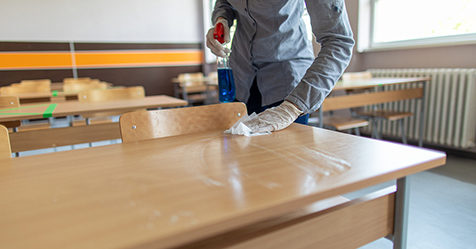Cleaning school desks while wearing PPE