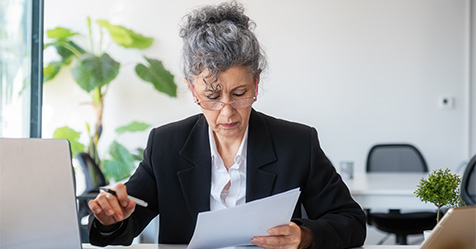 Senior gray-haired woman examines the contract